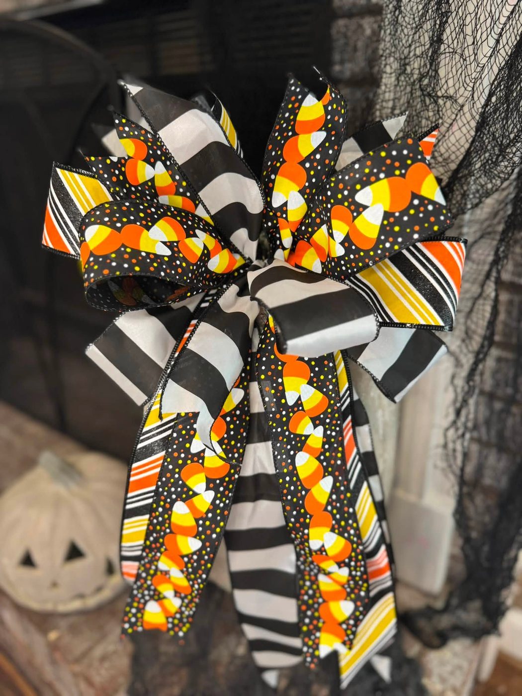 Layered black, white, and candy corn striped bow on a wreath stand